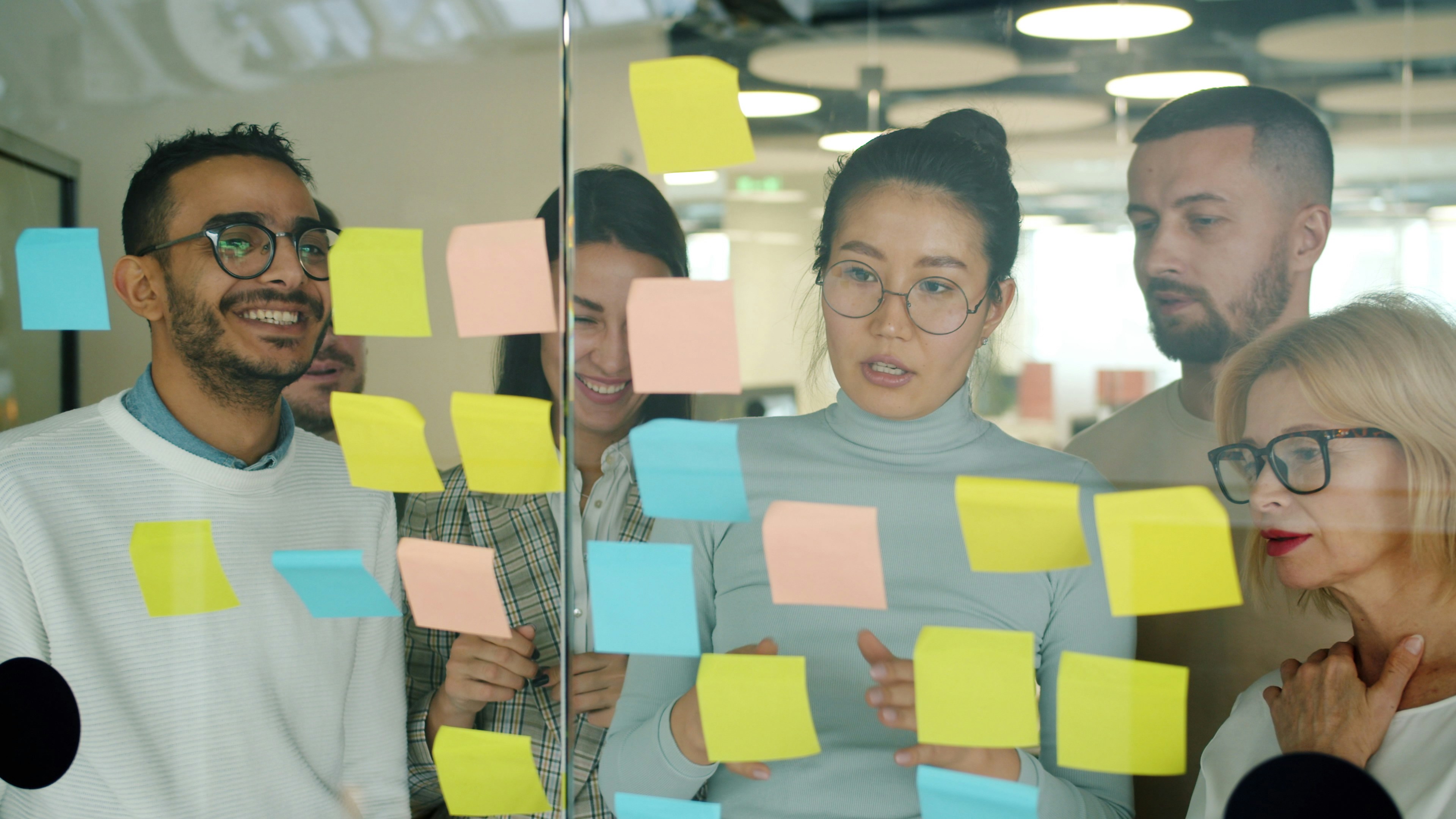 Office staff looking at post-it notes on wall